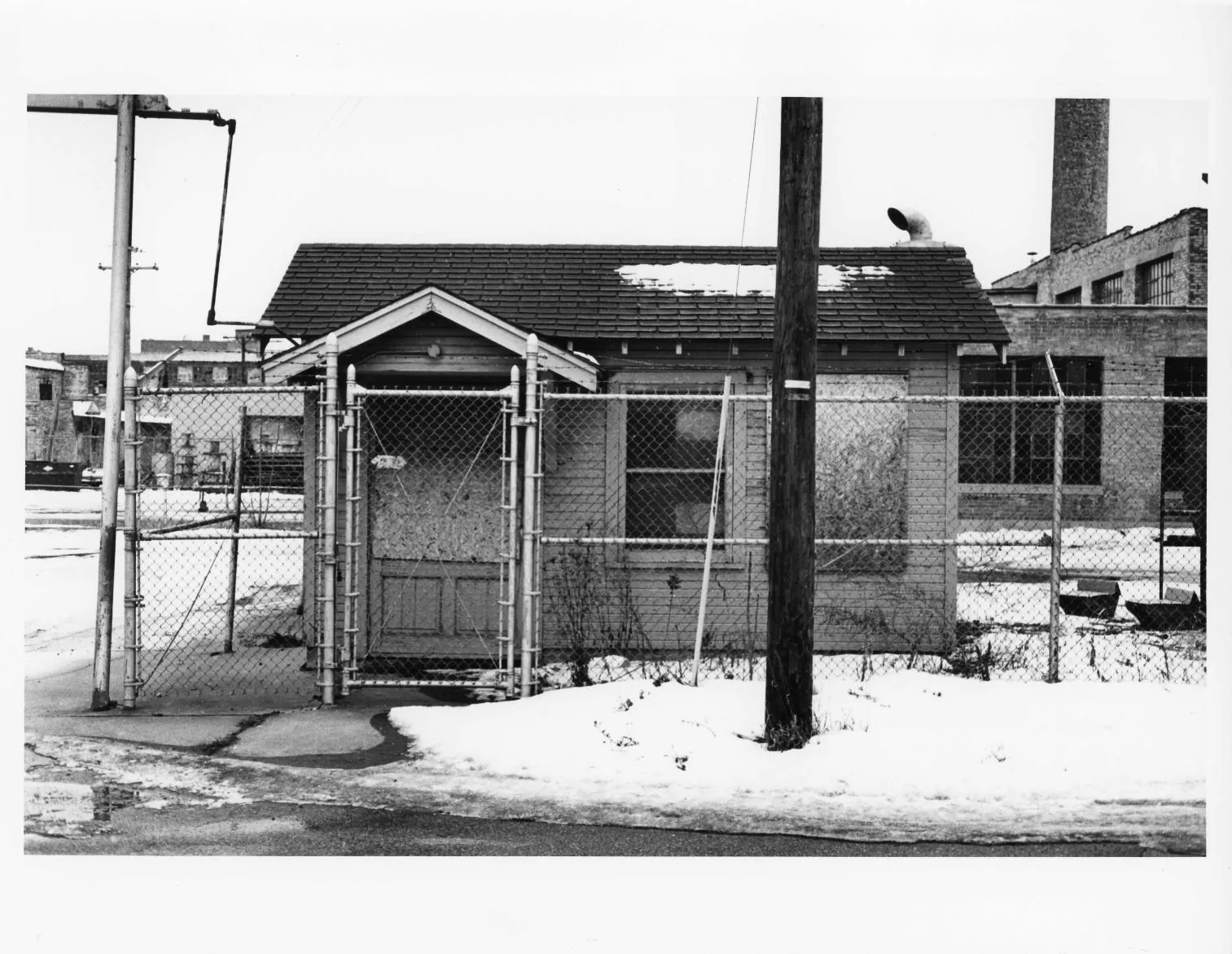 Black-and-white photographs of the Buescher Band Instrument Company Building, 1986: Detached Frame Shed Behind Fence (1986)